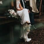 bride and groom sitting and holding their hands