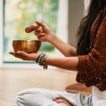 woman in brown knit sweater holding brown ceramic cup