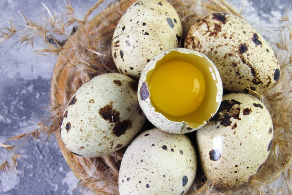 Quail eggs on a wooden board with broken yolk