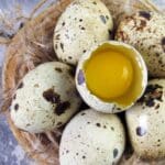 Quail eggs on a wooden board with broken yolk
