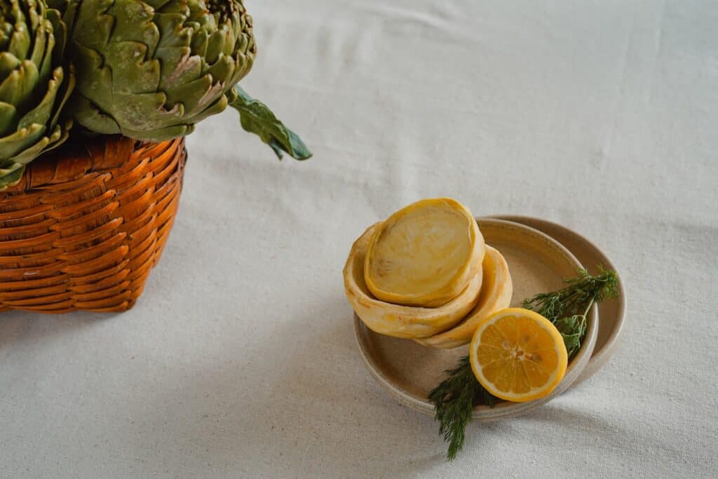 Fresh artichokes and prepared vegetables on a table.
