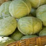 a basket filled with cabbage next to a pile of green apples