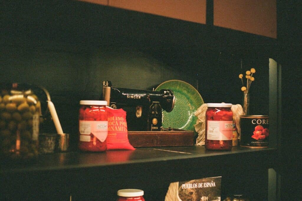 Jars of food and a sewing machine on a shelf.