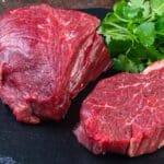 Two steaks on a plate with parsley