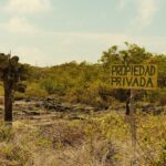 Private property sign in a dry, brushy landscape.